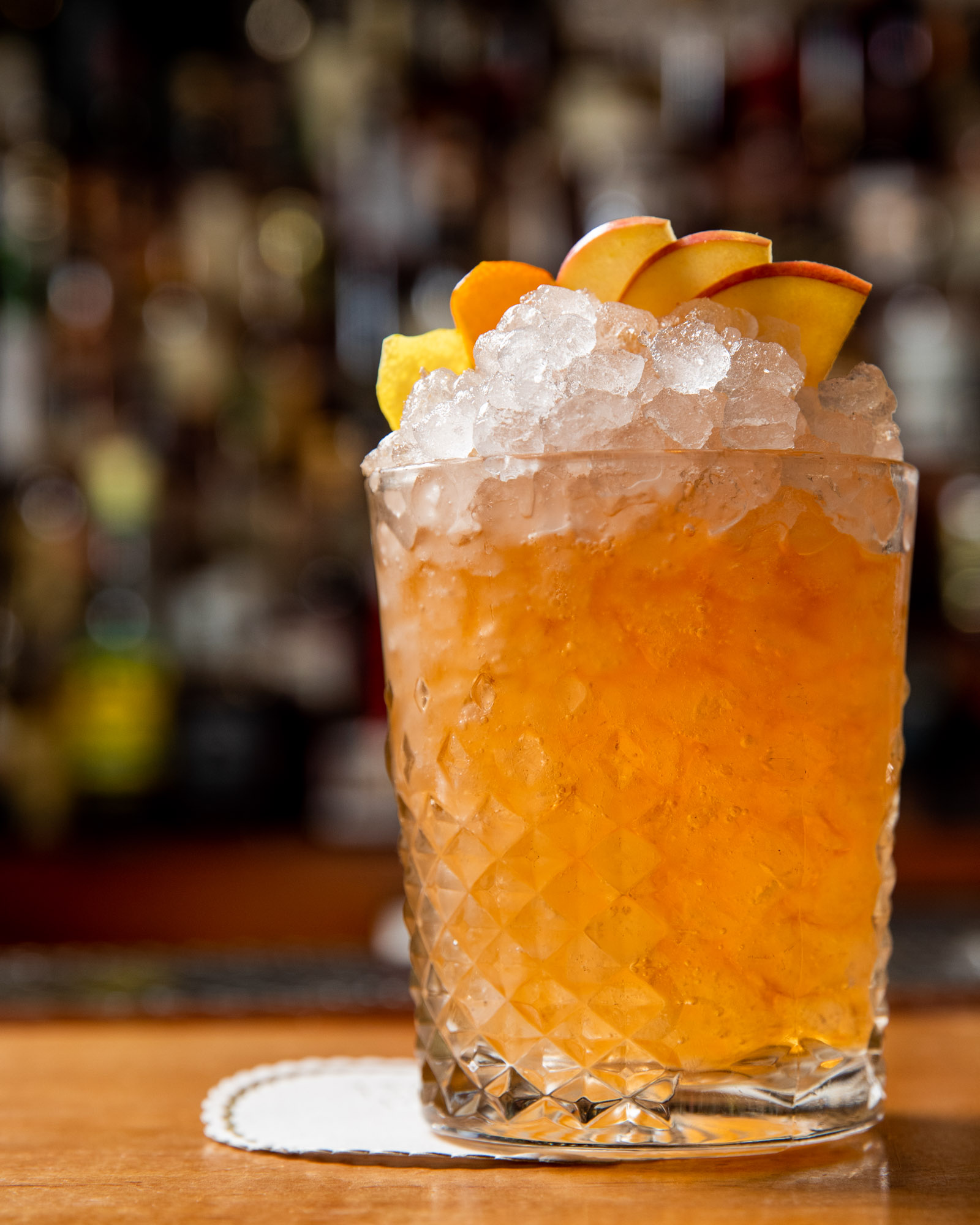 Tropical cocktail with a mound of ice and peach garnish
